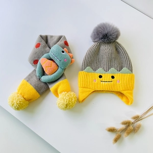 Detail of grey knitted kids hat and scarf set with cute dinosaur cartoon accents