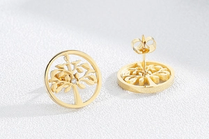Macro detail of golden tree of life stud earrings with small zircon stone inlay