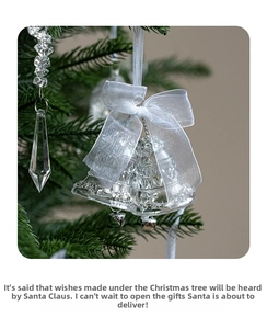 Close-up of clear Christmas bell ornaments with silver bows hanging on a green tree