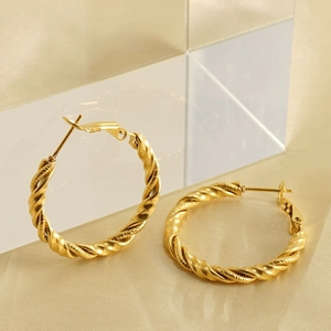 Twisted rope design 18k gold plated stainless steel hoop earrings on silk background