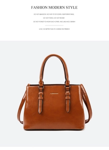 Detail of a brown glossy leather handbag with dual handles and a removable shoulder strap