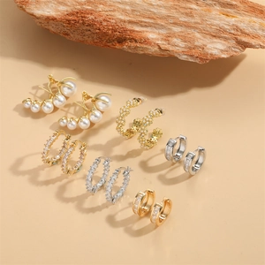 Elegant assortment of gold and silver floral zircon earrings with pearls on a wood stand