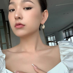 Close-up of elegant gold horseshoe earrings with micro-set zircons on a female model
