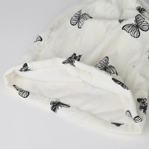 White knit beanie with black butterfly print and distressed fringe details in retro style