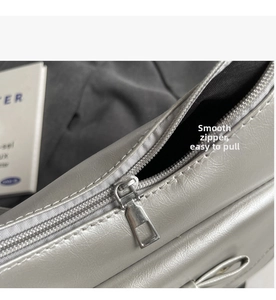 Close-up of smooth silver-grey leather tote bag with metal zipper and bow detail