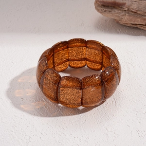 Detail eines Bernstein-Acryl-Armbands mit Goldglitzer und elastischem Gliederdesign