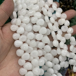 Close-up of hand holding a string of polished white water-drop crystal agate beads