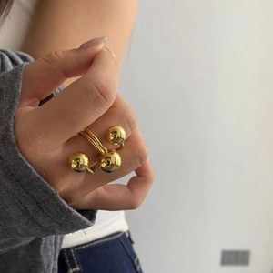 Close-up of gold plated triple ball ring on model's finger with a modern metallic finish