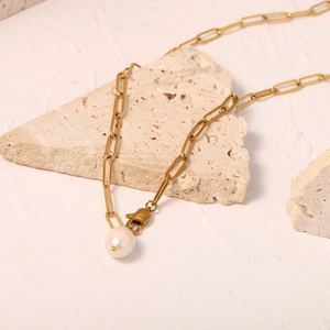 Gold paperclip link chain necklace featuring a white freshwater pearl pendant on stone