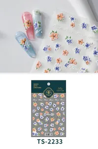 Detail of 3D embossed flower nail stickers in orange and blue on various nail tips