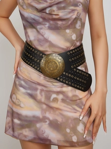 Detail of vintage gold round buckle with carvings on black PU leather belt for women
