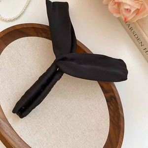 Détail d'une pince à cheveux banane élégante en tissu noir sur un plateau en bois