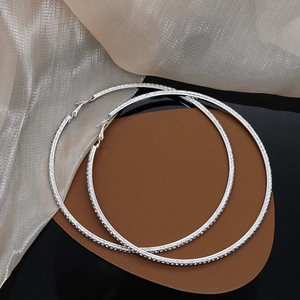 Sparkling silver hoop earrings with round rhinestones shown on elegant luxury background