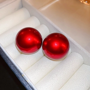 Close-up of vibrant red round earrings with a glossy finish on a white velvet display