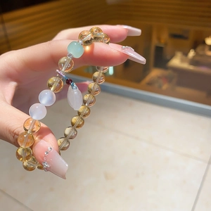 Close-up of yellow citrine and chalcedony crystal beaded bracelet with a pink droplet charm