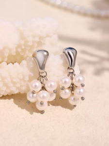 Macro view of grape-shaped cluster drop earrings with white pearls and silver metal studs