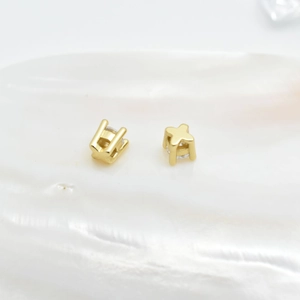 14K gold plated star stud earrings with clear zircon stones on a white pearl shell