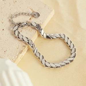 Detailed view of polished silver steel chain bracelet on a stone with gold fabric background