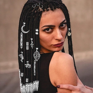 Detailed view of silver dreadlock accessories on hair braids with moon and leaf charms