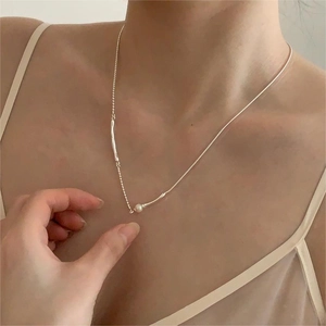 Minimalist silver chain necklace with a single white pearl shown on model neckline