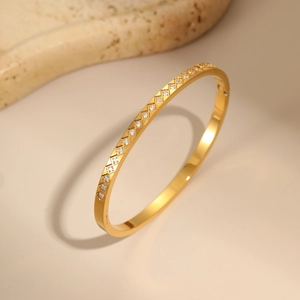 Macro detail of gold-plated lattice bangle featuring sparkling white zircon stone inlays