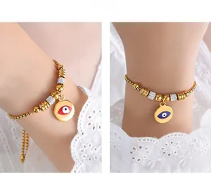 Detail of gold beaded bracelets with blue and red evil eye pendants and micro pavé accents