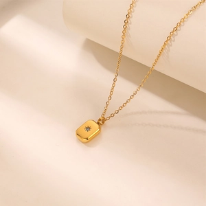 Close-up of golden rectangular pendant with star engraving and sparkling zircon stone