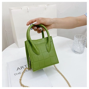 Detailed close-up of grass green mini crossbody bag with crocodile embossed leather and chain