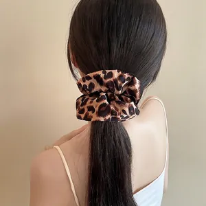Elegant leopard print oversized satin scrunchie shown on a woman's hair in a low bun
