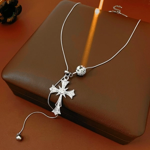 Detailed view of silver cross pendant with rhinestones and spotted tiger eye bead