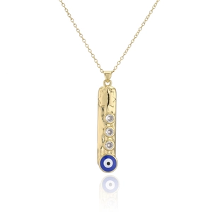 Detailed shot of a gold bar pendant featuring star relief, gems and blue evil eye motif
