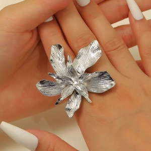Macro detail of large silver flower ring featuring artistic brushed metal texture petals