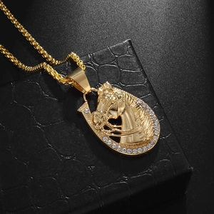 Macro shot of gold horse head pendant with sparkling rhinestones on black leather box