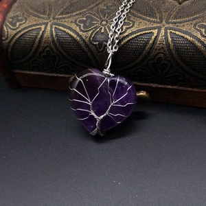 Macro view of purple amethyst tree of life heart pendant on dark leather box