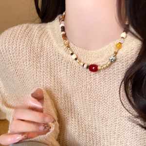 Nahaufnahme der Boho-Halskette mit Achat und gepunkteten Steinen auf Strickpullover