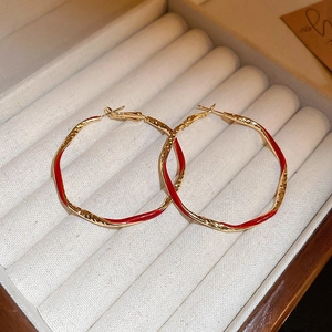Close-up of red and gold textured hoop earrings in a beige velvet jewelry box