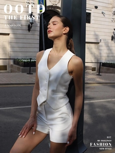 Outdoor street view of a slim-fit white suit vest and matching high-waist shorts set