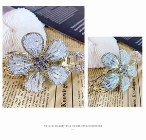 Detailed view of the sparkling floral claw clip with white zircons and gold base