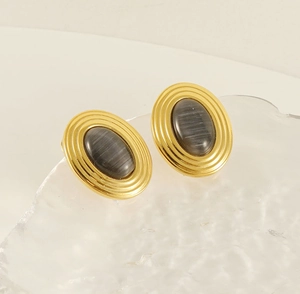 Detailed macro view of vintage oval 18K gold plated earrings with dark grey gemstone inlay