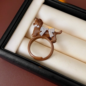 Detail of dachshund ring featuring a pearl necklace and rhinestone bow in a jewelry box
