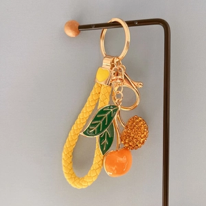 Close-up of cute cherry keychain with orange rhinestones and yellow braided leather loop
