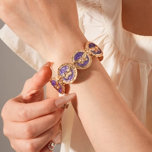 Detailed close-up of vintage gold bracelet with purple enamel and gold butterfly motifs