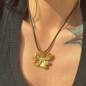 Detail of 18k gold plated flower pendant with sparkling cubic zirconia on black cord