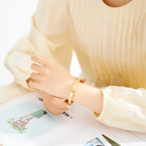 18K gold plated cuff bracelet with blue evil eye charms on a fashion model's wrist