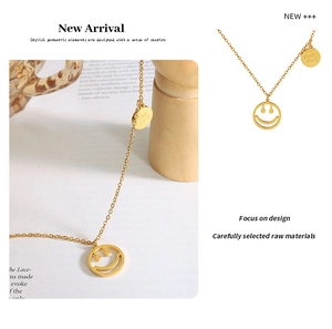 Detalle del collar dorado con colgante de cara sonriente y grabado Good Luck en el disco