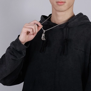Detail of silver boxing glove pendant on a twisted chain held by a male model