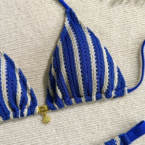 Gros plan d'un haut de bikini en crochet rayé bleu et blanc avec pendentif coquillage