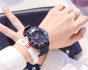 Wrist shot of black quartz watch with silicone strap and matching white rubber bracelet