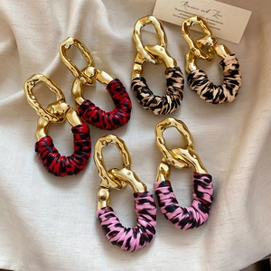 Detail of three pairs of large geometric earrings featuring varied animal print fabrics