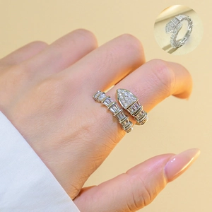 Silver-tone snake ring with pavé crystals on a minimal warm beige background